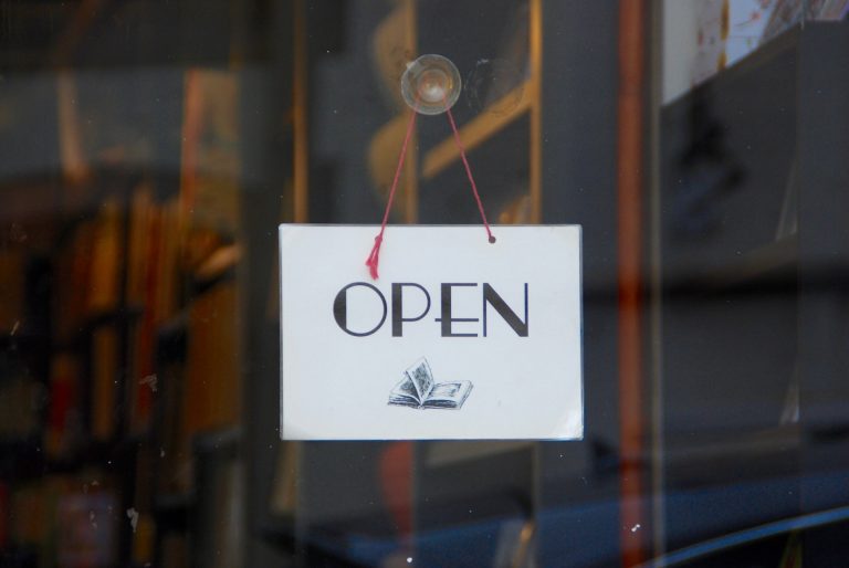 Myymälän ovessa roikkuva kyltti, jossa lukee "open".